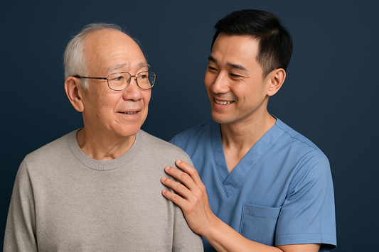 A clean and professional image of an elderly East Asian man smiling with a younger male caregiver beside him, set against a navy background, conveying trust and reassurance in a caregiving context.