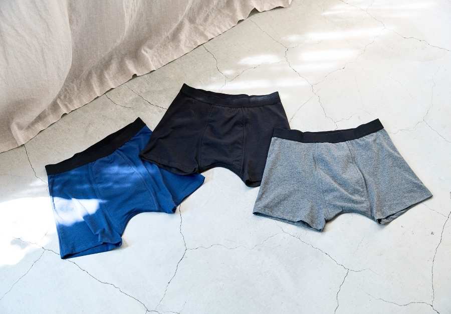 ネイビー・ブラック・グレーの3色のボクサーパンツが床に並べられた写真。男性用尿漏れパンツの選び方ガイド。